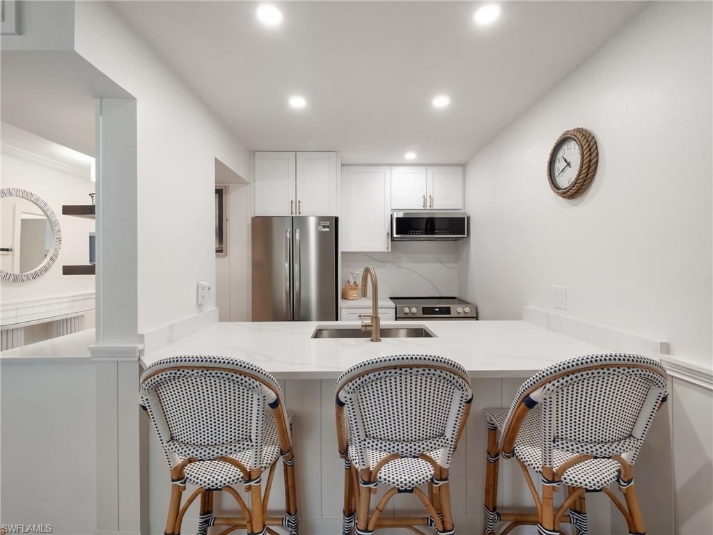 3113 Tennis Villas Captiva, FL 33924 - Photo 22 of 48 a kitchen with stainless steel appliances granite countertop a dining table chairs refrigerator and microwave
