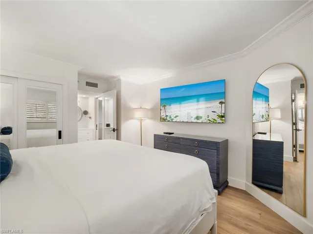 a large white bed in a bedroom and dresser