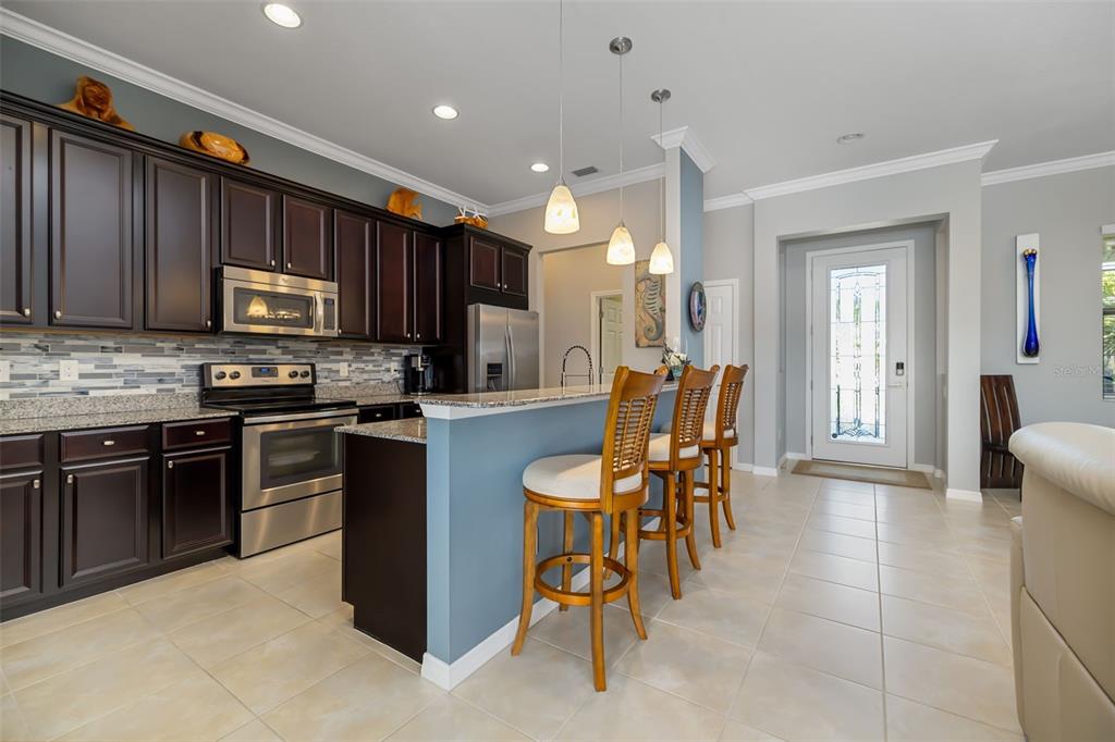 12844 24th St Circle East Parrish, FL 34219 - Photo 12 of 57 a kitchen with stainless steel appliances granite countertop a stove top oven a sink dishwasher a dining table and chairs