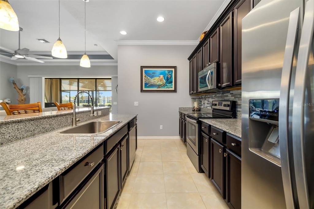 12844 24th St Circle East Parrish, FL 34219 - Photo 13 of 57 a large kitchen with stainless steel appliances granite countertop a sink and a refrigerator