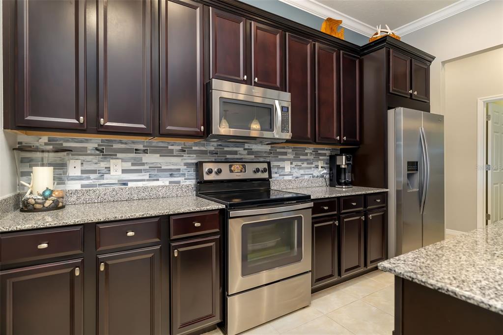 12844 24th St Circle East Parrish, FL 34219 - Photo 10 of 57 a kitchen with granite countertop wooden cabinets and stainless steel appliances