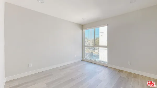an empty room with wooden floor and window
