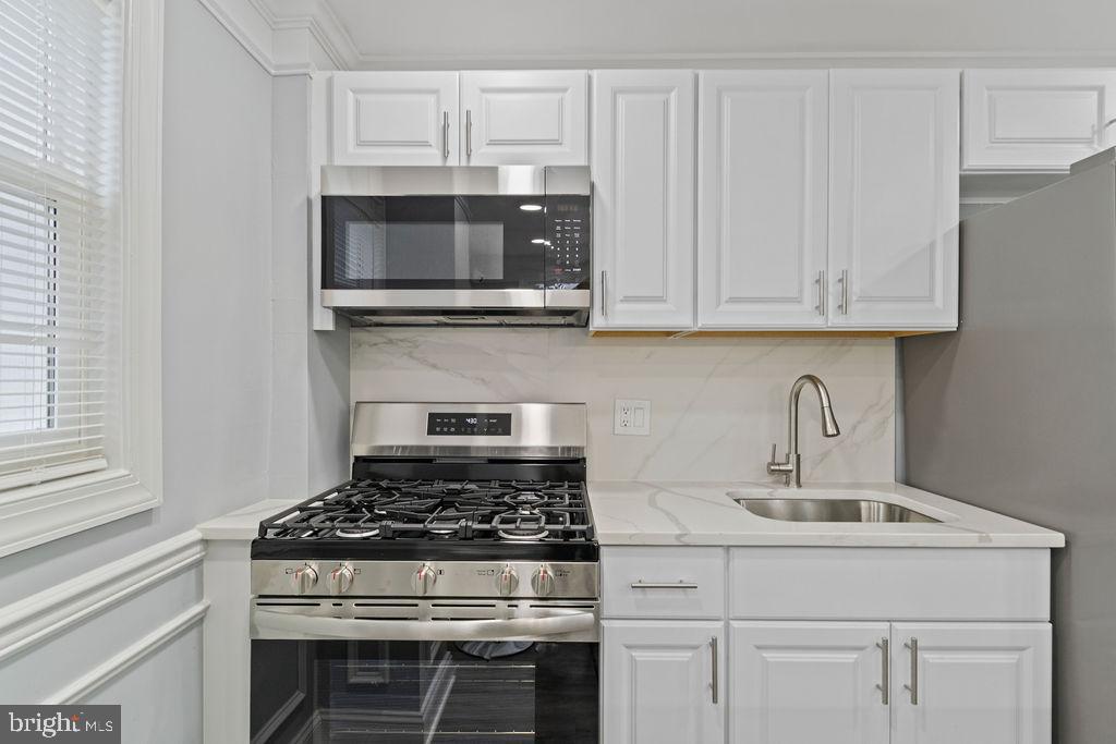 300 Denison Street Baltimore, MD 21229 - Photo 24 of 26 a kitchen with granite countertop a stove and a white cabinets
