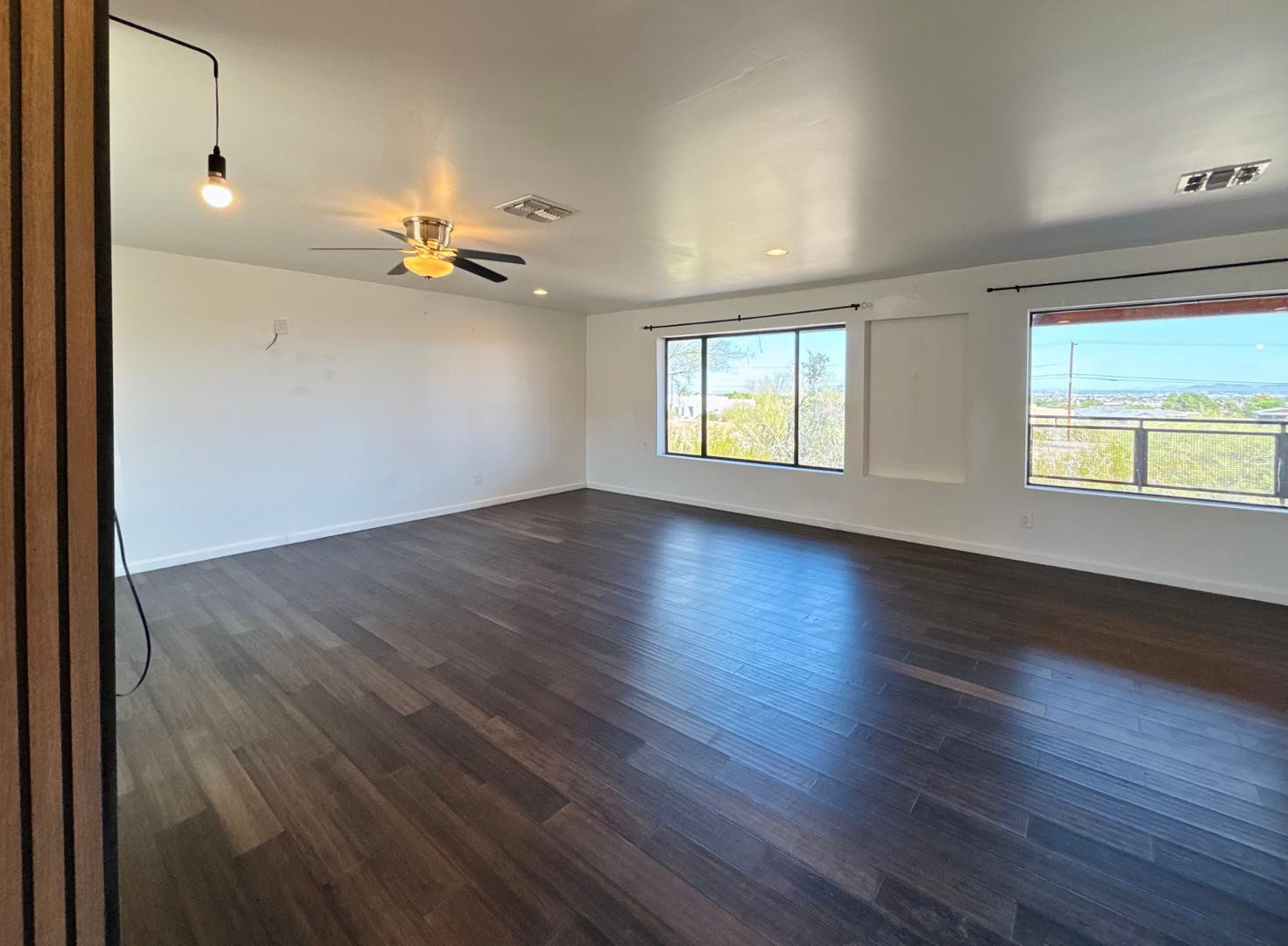 1750 West Pearce Road Phoenix, AZ 85041 - Photo 7 of 39 an empty room with wooden floor chandelier fan and windows