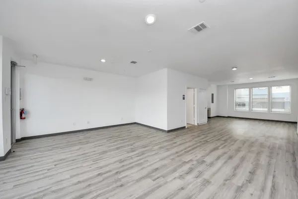 a view of an empty room with wooden floor and windows