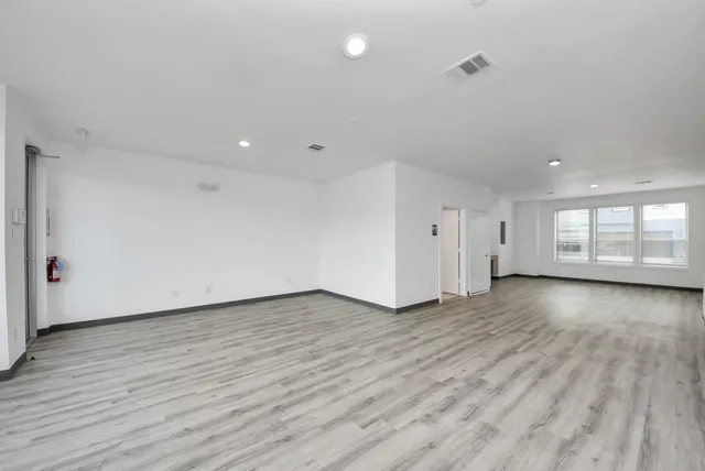 a view of an empty room with wooden floor and windows