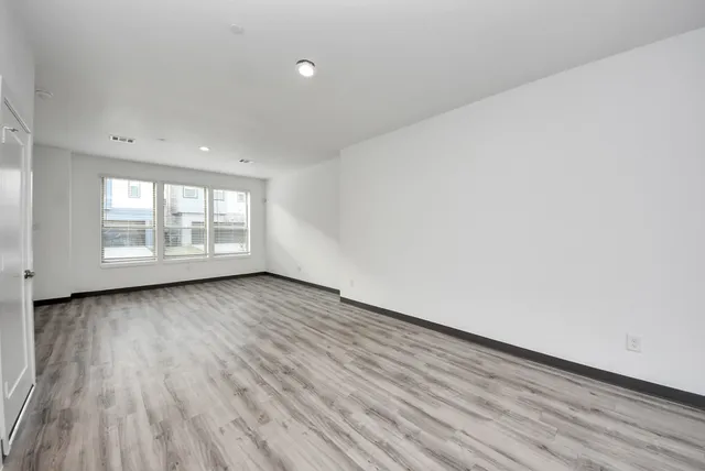 an empty room with wooden floor and windows