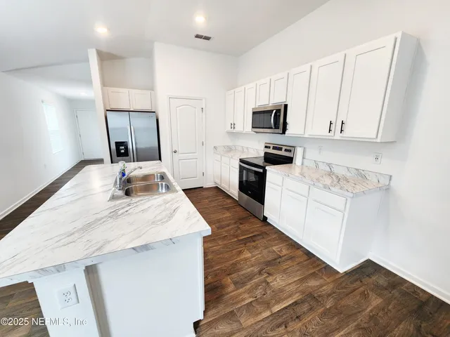 a large kitchen with kitchen island a sink dishwasher a stove and a microwave oven with wooden floor