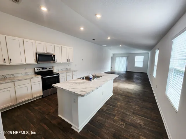 a view of a hallway with wooden floor and a bathroom