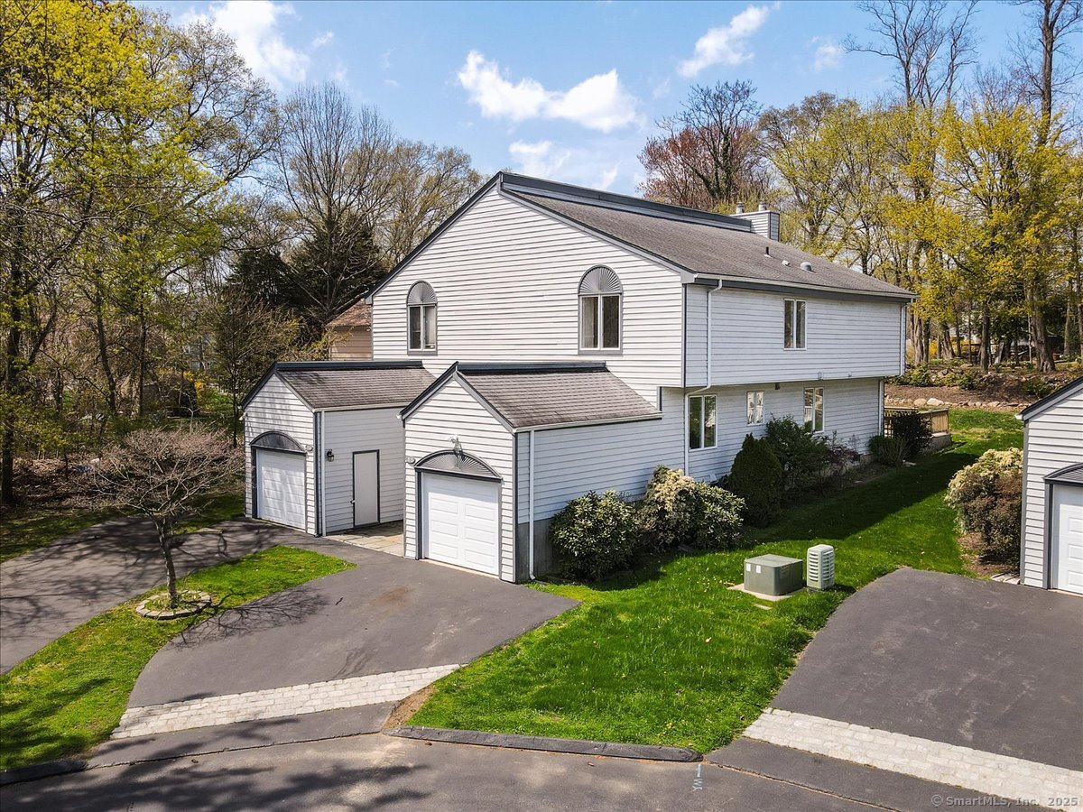 375 High Street, Unit 375 Fairfield, CT 06824 - Photo 1 of 1 a view of a white house next to a yard with potted plants and large trees