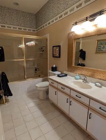 a spacious bathroom with a double vanity sink toilet mirror and shower