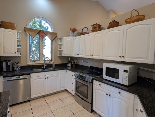 a kitchen with granite countertop a sink a stove and cabinets