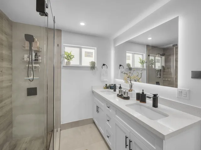 a bathroom with a double vanity sink a mirror and shower