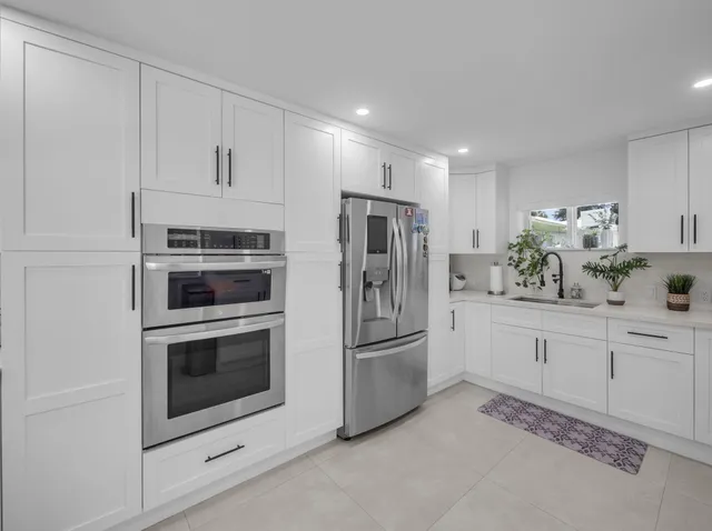 a kitchen with granite countertop white cabinets and stainless steel appliances