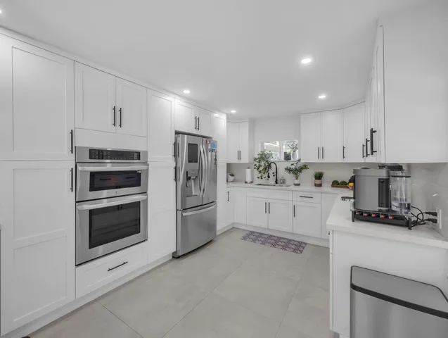 a kitchen with white cabinets and stainless steel appliances