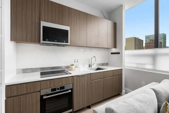 a kitchen with stainless steel appliances a sink a stove a microwave cabinets and a counter top space