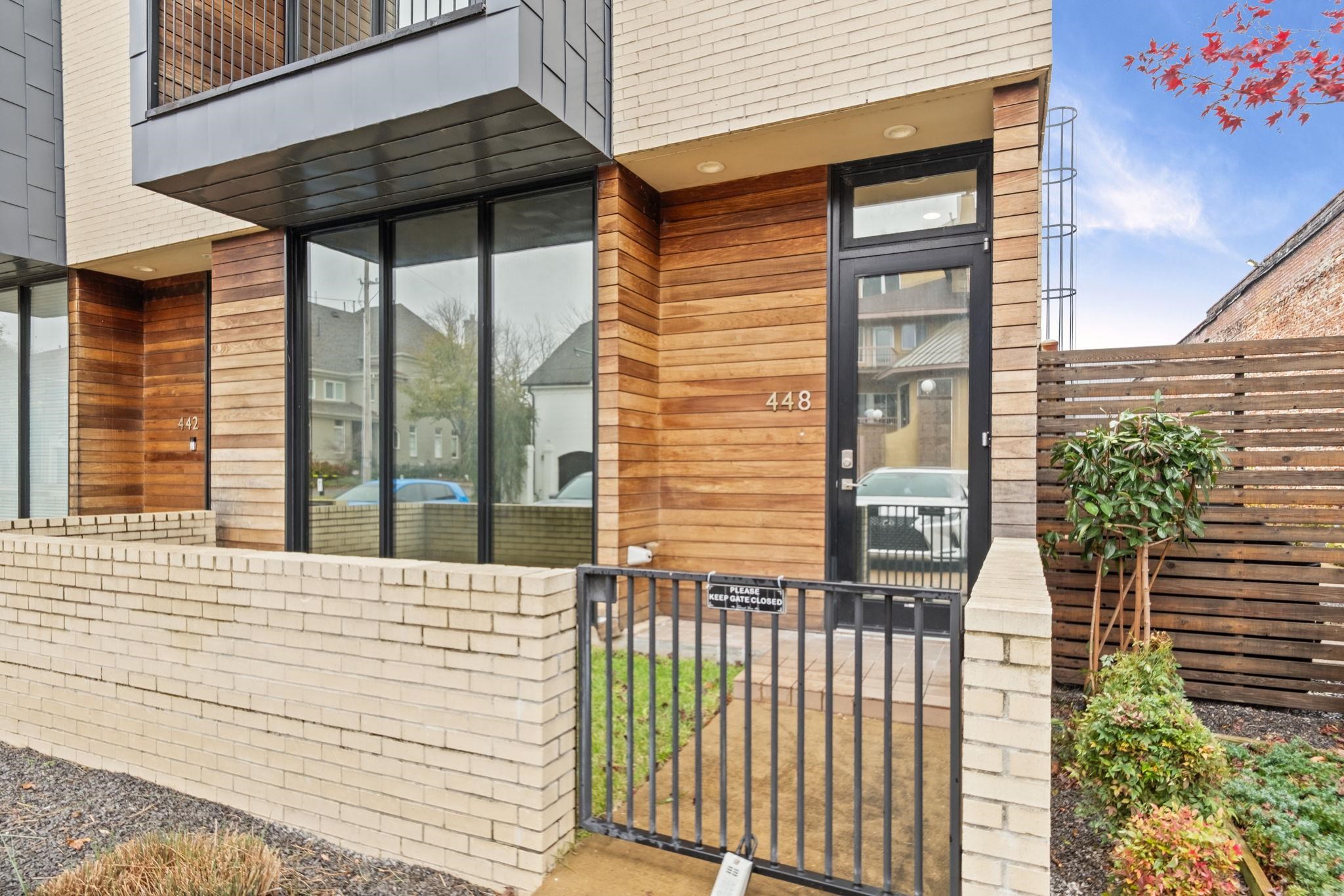 448 Tennessee Street Memphis, TN 38103 - Photo 2 of 39 Contemporary exterior featuring a wood-panel accent wall, full-light entry door, and large floor-to-ceiling windows