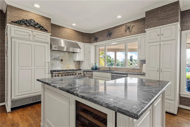 a kitchen with stainless steel appliances granite countertop a sink a stove and a wooden floors