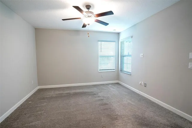 an empty room with a window and a fan