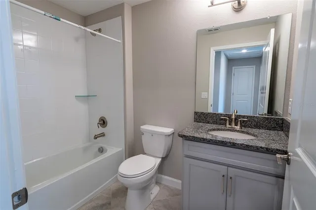 a bathroom with a granite countertop sink a toilet and shower