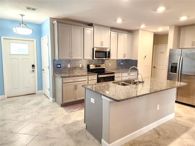 a kitchen with stainless steel appliances granite countertop a sink stove and refrigerator