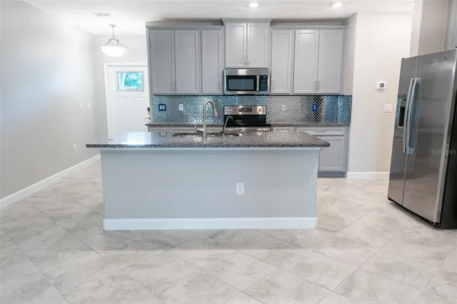 a kitchen with stainless steel appliances granite countertop a sink a stove a refrigerator a microwave and cabinets