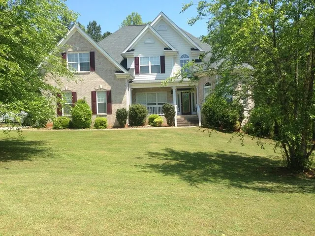 a view of a white house with a big yard and large trees