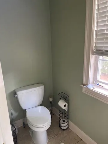a white toilet sitting next to a window and a sink