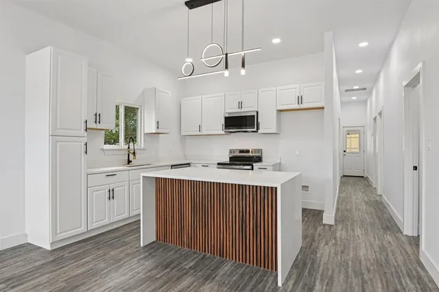 a kitchen with kitchen island white cabinets stainless steel appliances a sink and a refrigerator
