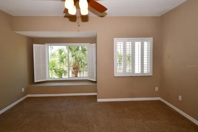 en view of an empty room with wooden floor and a ceiling fan