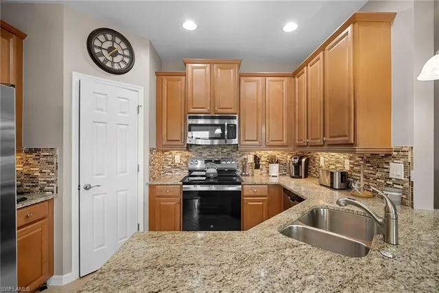 a kitchen with stainless steel appliances granite countertop a sink a stove a refrigerator and cabinets