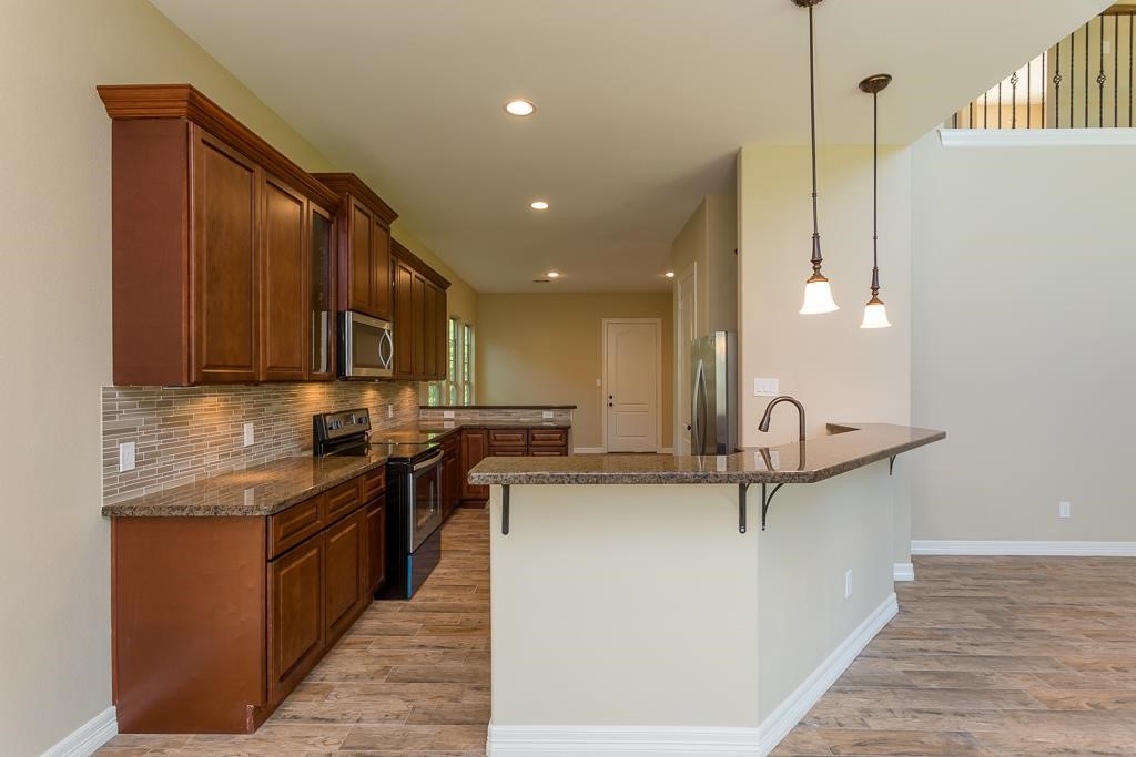 8403 Oak Knot Drive Spring, TX 77389 - Photo 11 of 31 a kitchen with stainless steel appliances granite countertop a sink a stove and a wooden floors