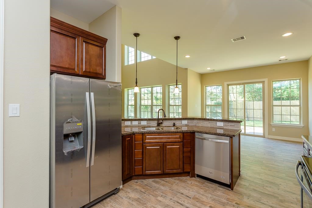 8403 Oak Knot Drive Spring, TX 77389 - Photo 13 of 31 a kitchen with stainless steel appliances granite countertop a refrigerator a sink a stove and white cabinets with wooden floor