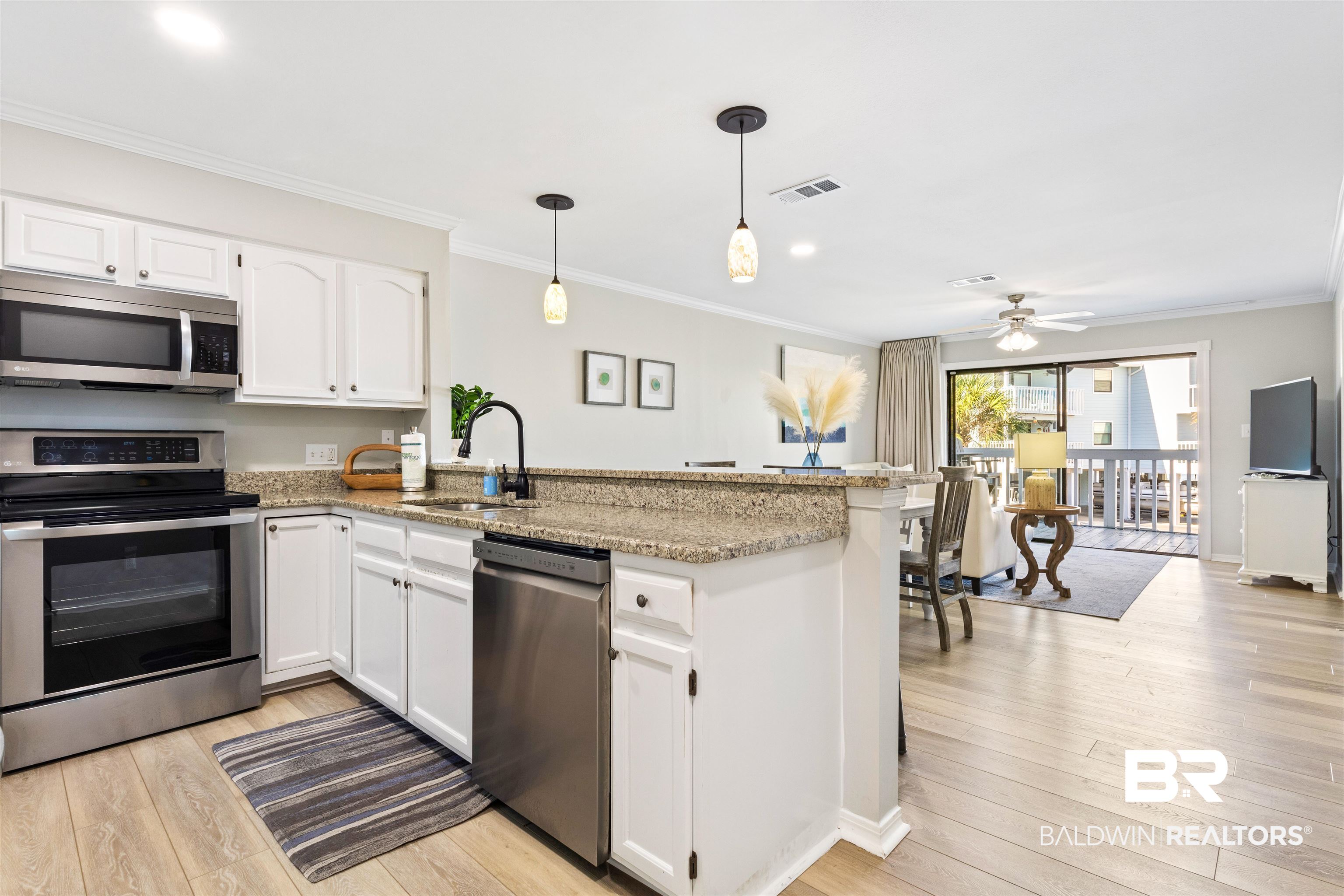 25861 Canal Road, Unit 3 Orange Beach, AL 36561 - Photo 6 of 40 Kitchen with appliances with stainless steel finishes, white cabinetry, pendant lighting, crown molding, and a peninsula