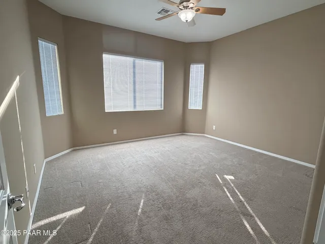 an empty room with windows and fan