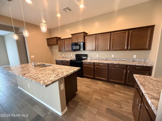 a kitchen with stainless steel appliances granite countertop a sink refrigerator and microwave