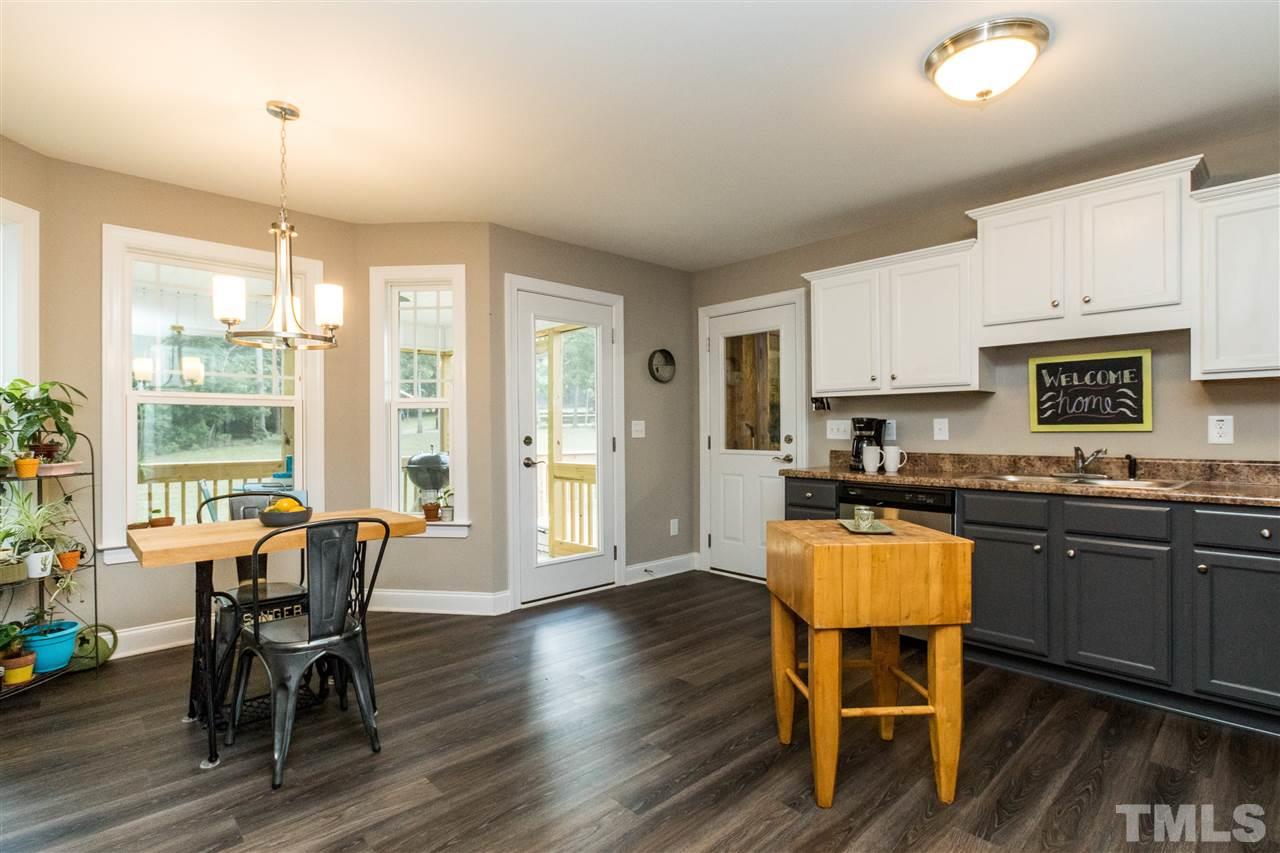 44 Henry Rifle Lane Angier, NC 27501 - Photo 7 of 22 a kitchen with stainless steel appliances granite countertop a stove a refrigerator a kitchen island with a dining table and chairs