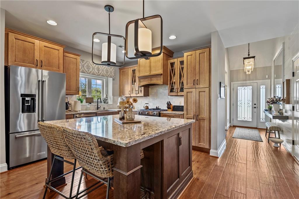 107 Resolution Drive Mars, PA 16046 - Photo 4 of 44 a kitchen with stainless steel appliances granite countertop a kitchen island a stove a refrigerator a oven a sink a dining table and chairs with wooden floor