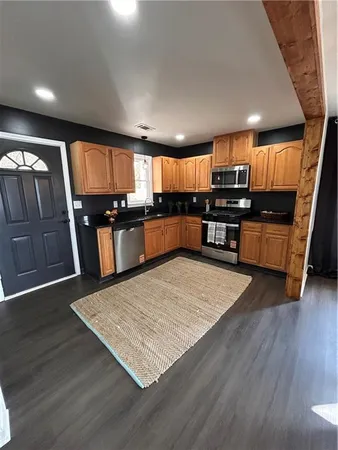 a kitchen with stainless steel appliances wooden floors wooden cabinets a refrigerator and microwave