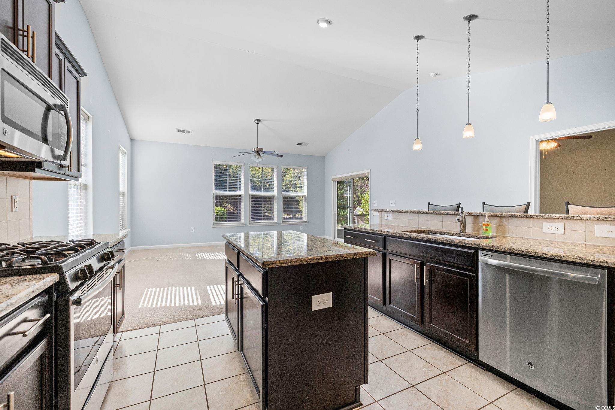 817 Arezzo Way, Unit 1001 Myrtle Beach, SC 29579 - Photo 18 of 40 Kitchen featuring ceiling fan, tasteful backsplash, appliances with stainless steel finishes, a center island, and high vaulted ceiling