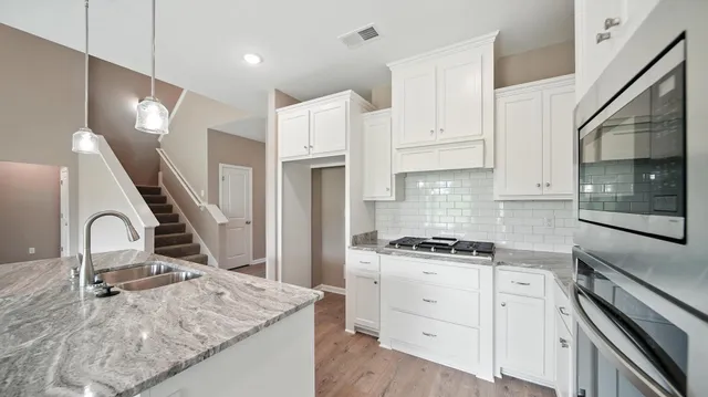 a kitchen with white cabinets and appliances