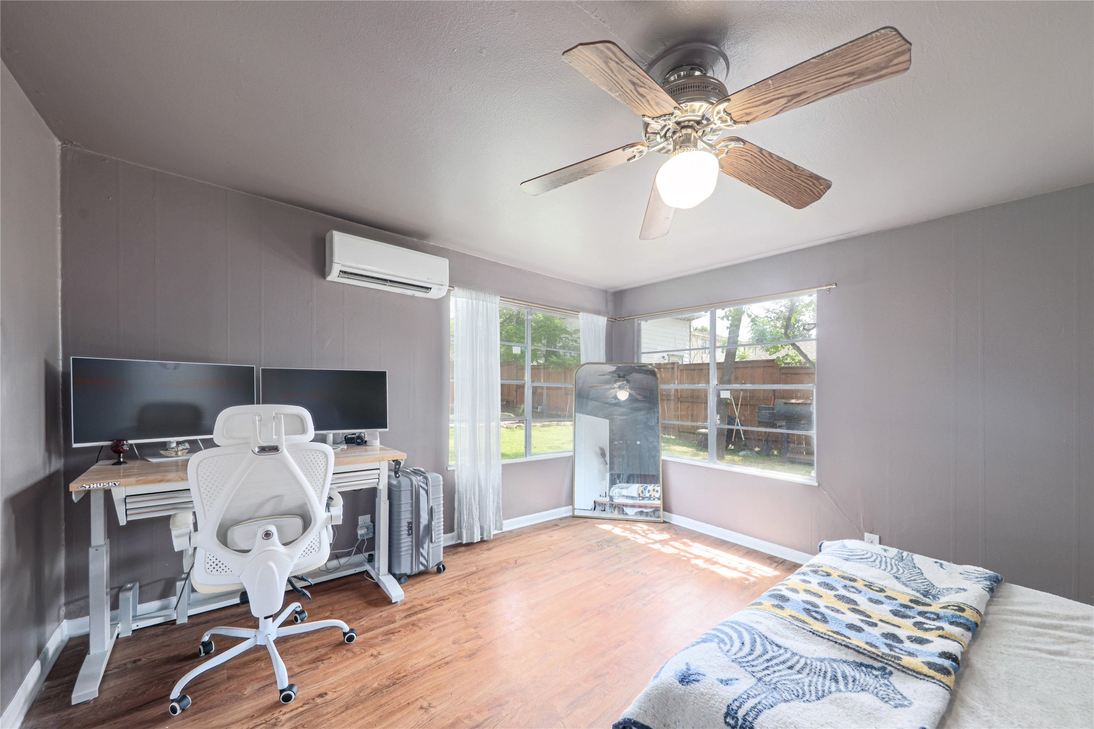 4607 Evans Avenue, Unit B Austin, TX 78751 - Photo 14 of 34 Room featuring wood-finish flooring, two large windows, a ceiling fan with light fixture, and a wall-mounted mini-split AC unit