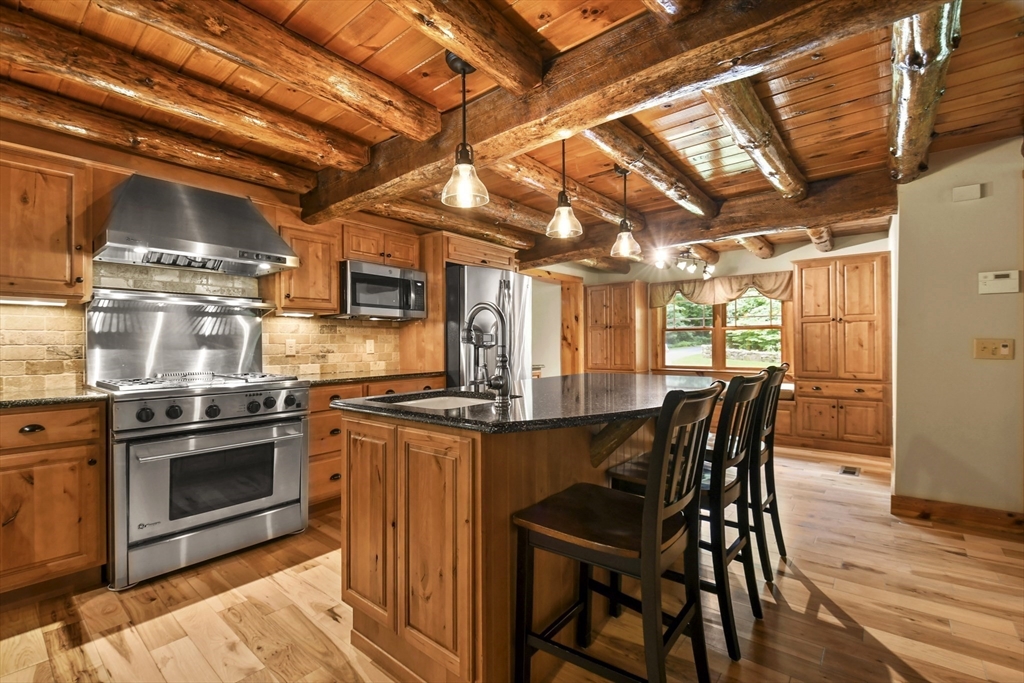 389 Kelly Road Northbridge, MA 01534 - Photo 8 of 40 a kitchen with stainless steel appliances granite countertop a stove a refrigerator a dining table and chairs with wooden floor