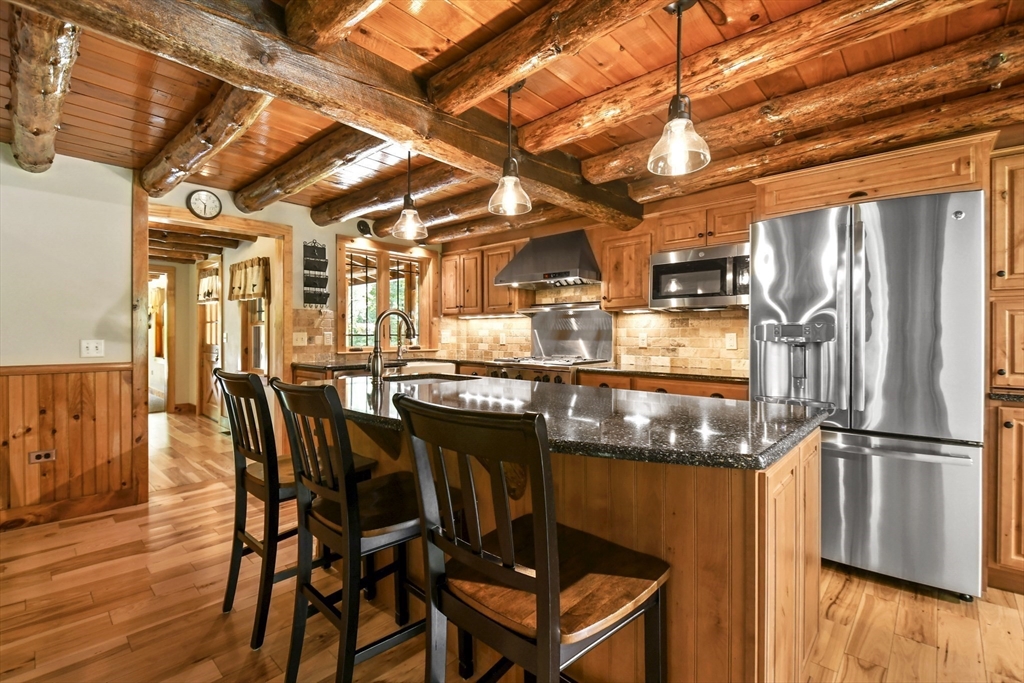 389 Kelly Road Northbridge, MA 01534 - Photo 9 of 40 a kitchen with stainless steel appliances granite countertop a table chairs and wooden floors
