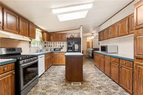 a kitchen with stainless steel appliances granite countertop a stove top oven a sink a counter space and cabinets