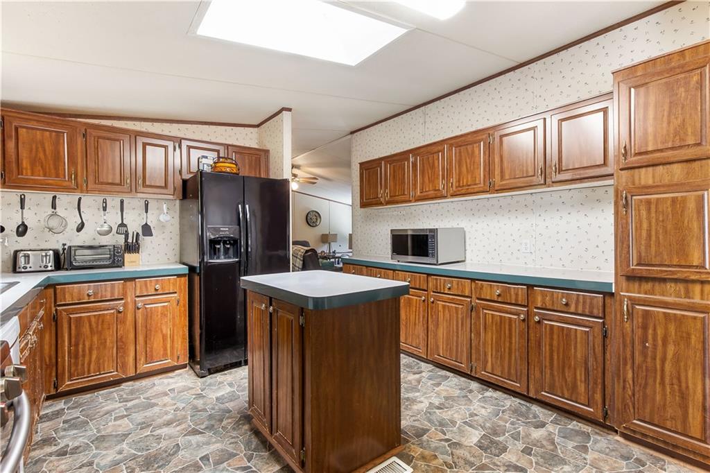 294 Birch Road Franklin, GA 30217 - Photo 7 of 30 a kitchen with stainless steel appliances granite countertop a refrigerator a sink dishwasher and wooden cabinets with wooden floor