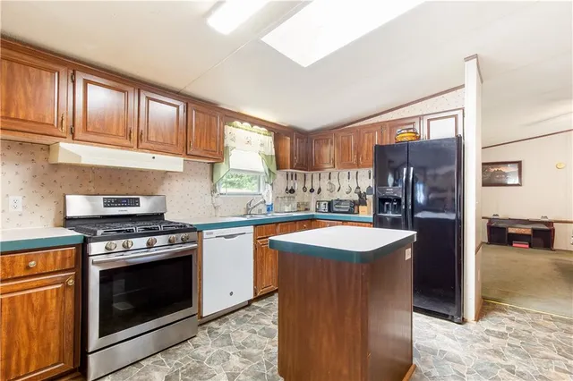 a kitchen with stainless steel appliances granite countertop a stove refrigerator and a sink