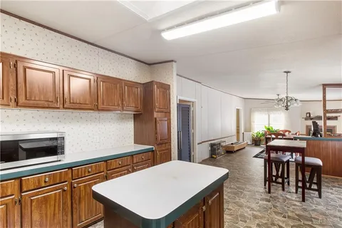 a kitchen with stainless steel appliances granite countertop a stove a refrigerator a kitchen island a dining table and chairs with wooden floor