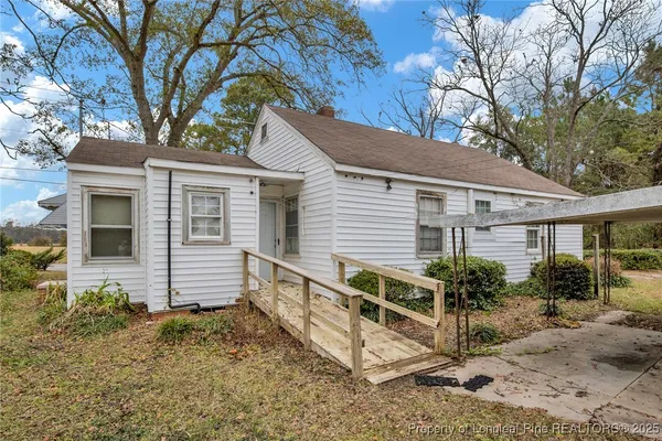 a view of house with a yard and large tree