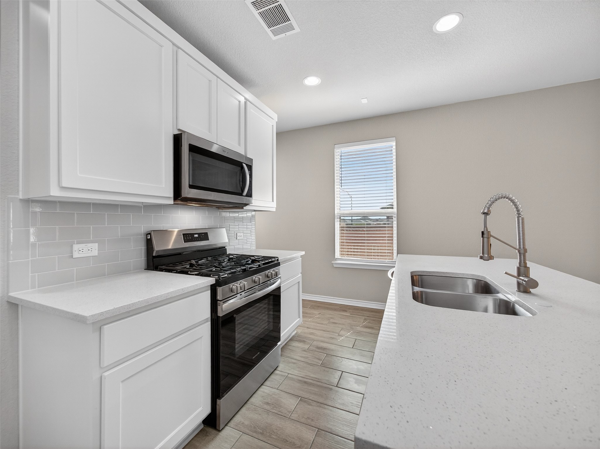 521 Rearing Mare Pass Georgetown, TX 78626 - Photo 11 of 39 a kitchen with stainless steel appliances granite countertop a sink and a stove top oven with wooden floor